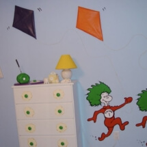Another view including the painting, kites, green eggs and ham sculpture and dresser.